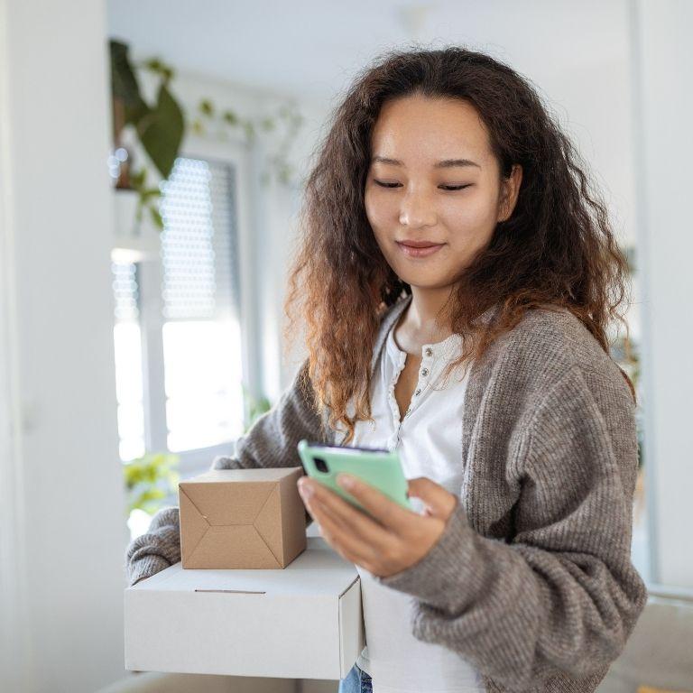 woman with packages looking at smartphone